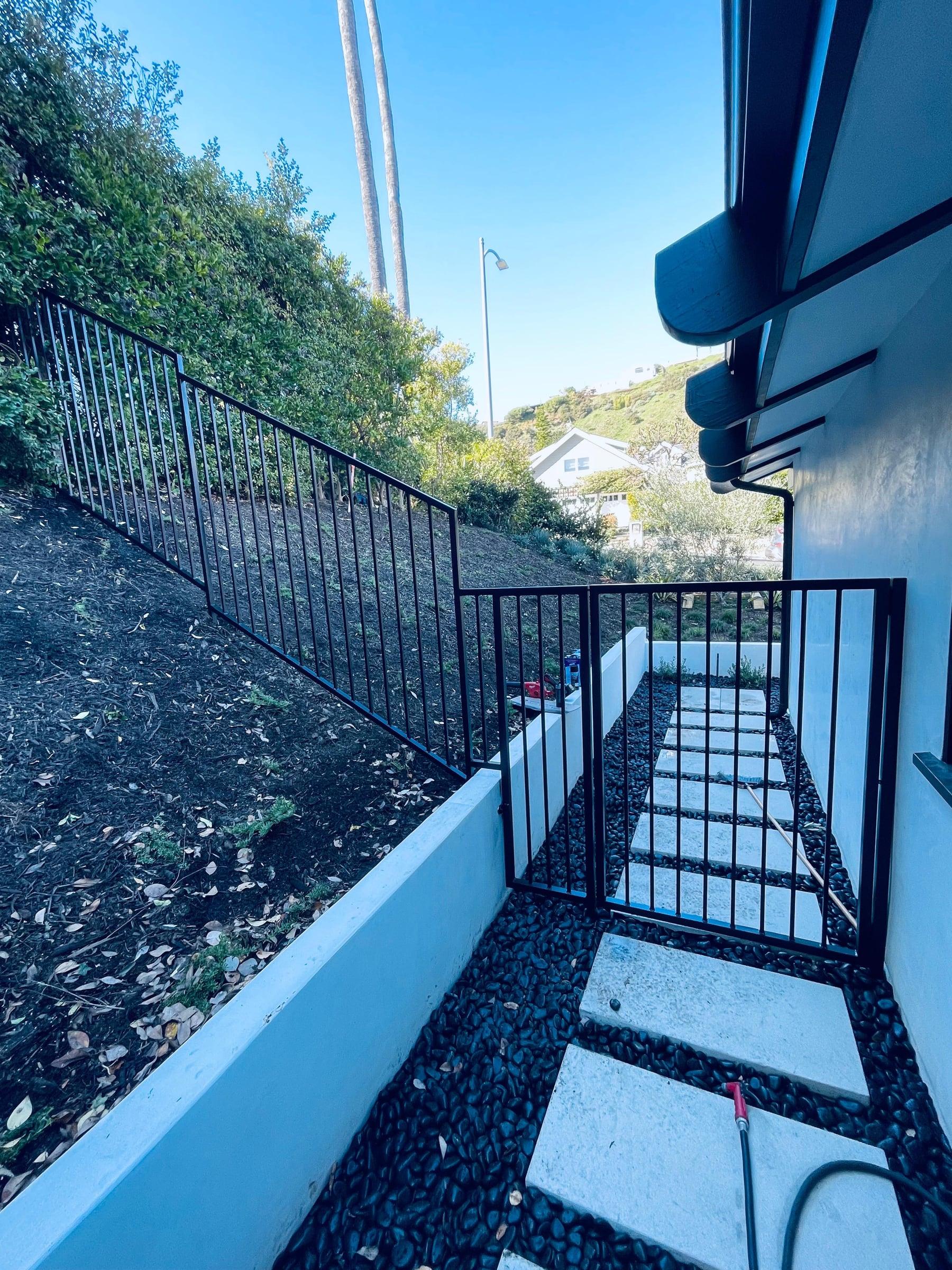Black iron handrail installed alongside concrete entry steps