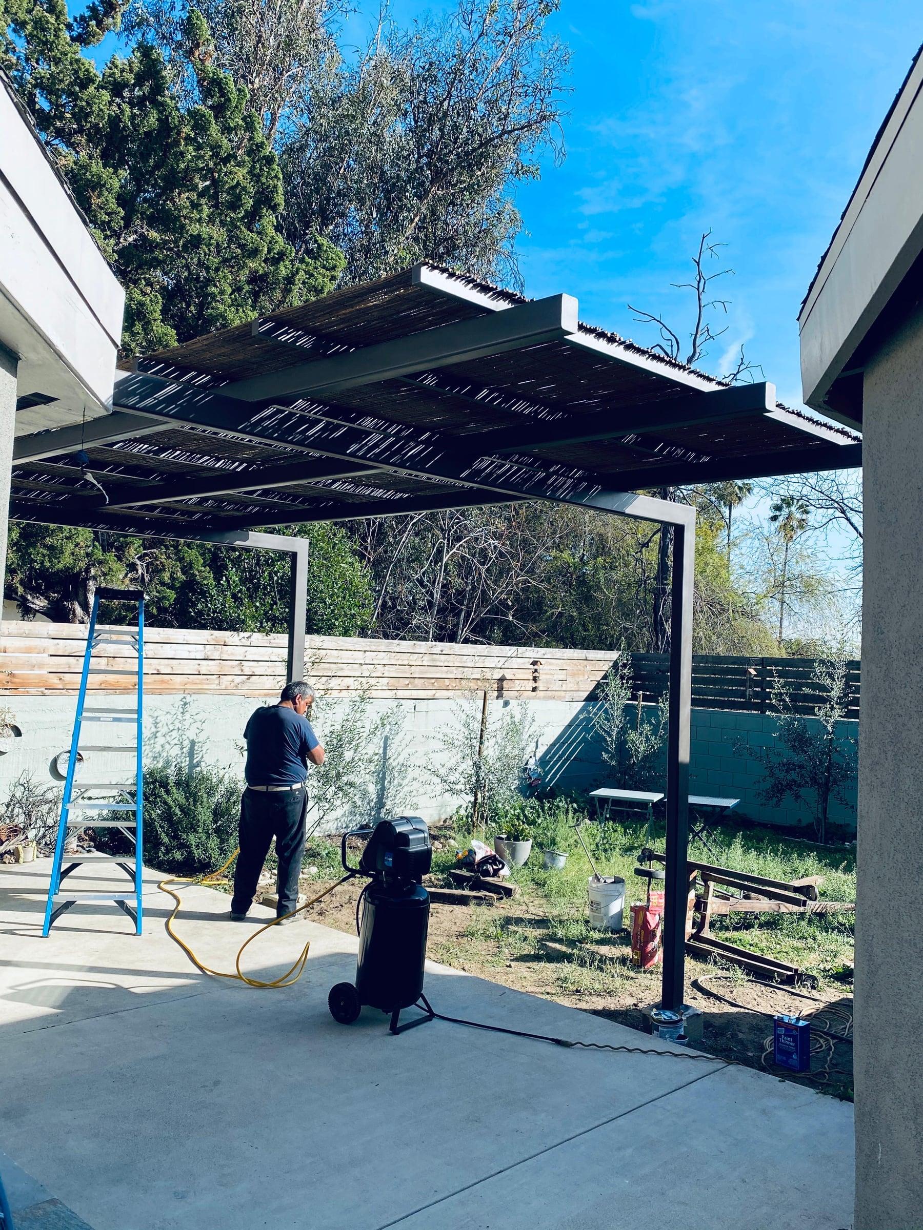 Custom metal patio cover structure under construction in a backyard