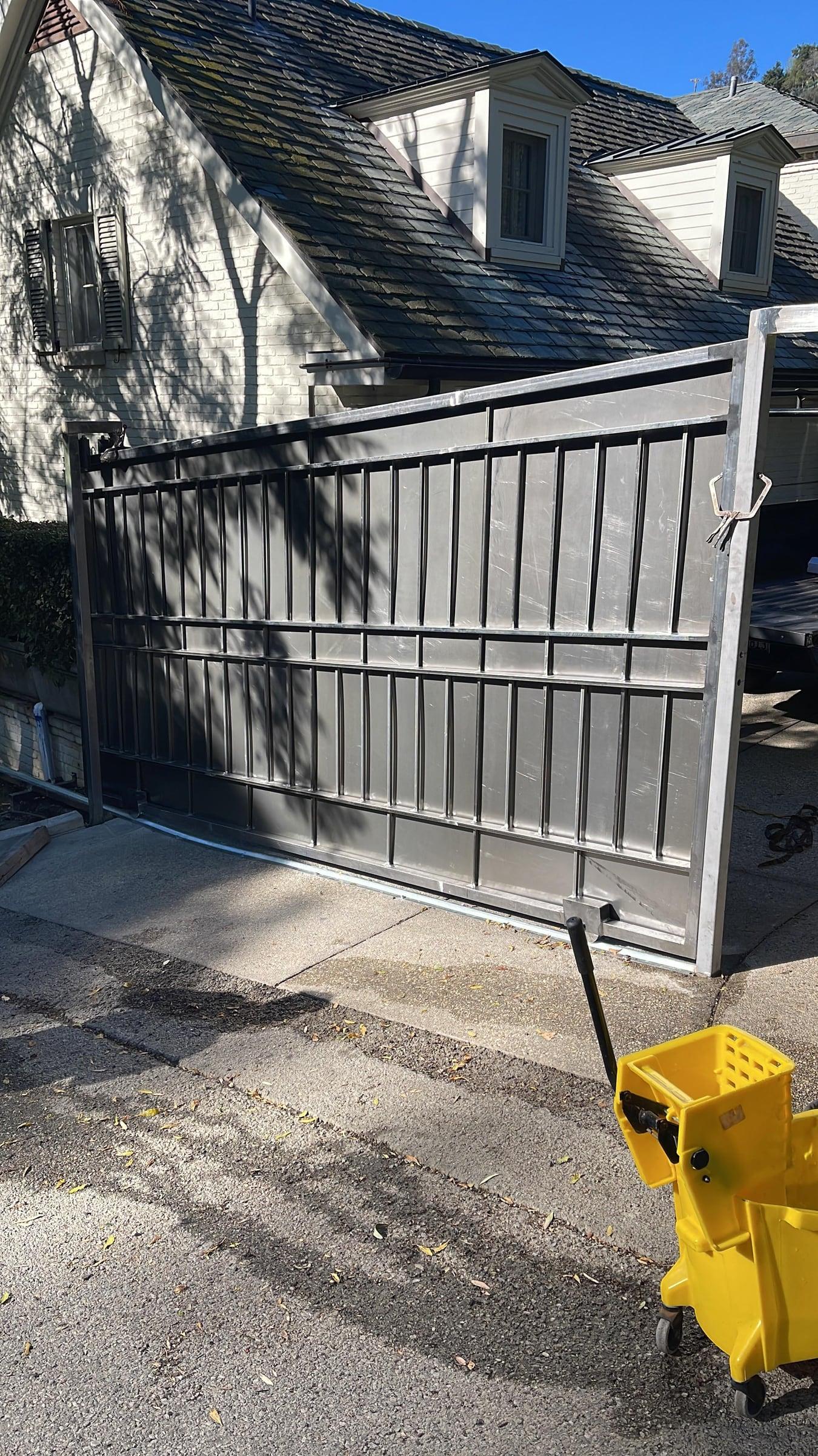 Bare metal driveway gate mid-installation prior to final finish