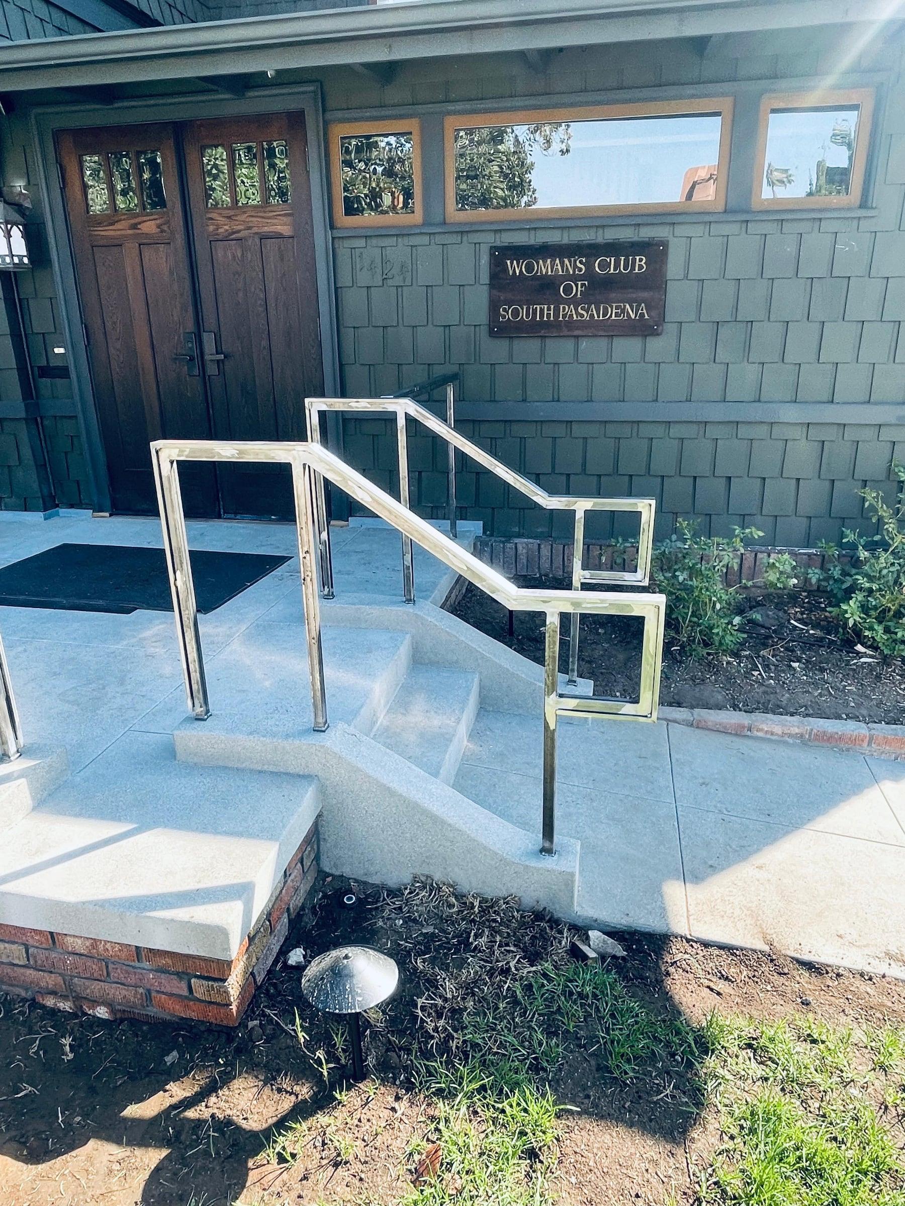 Polished metal handrail installed along exterior building steps