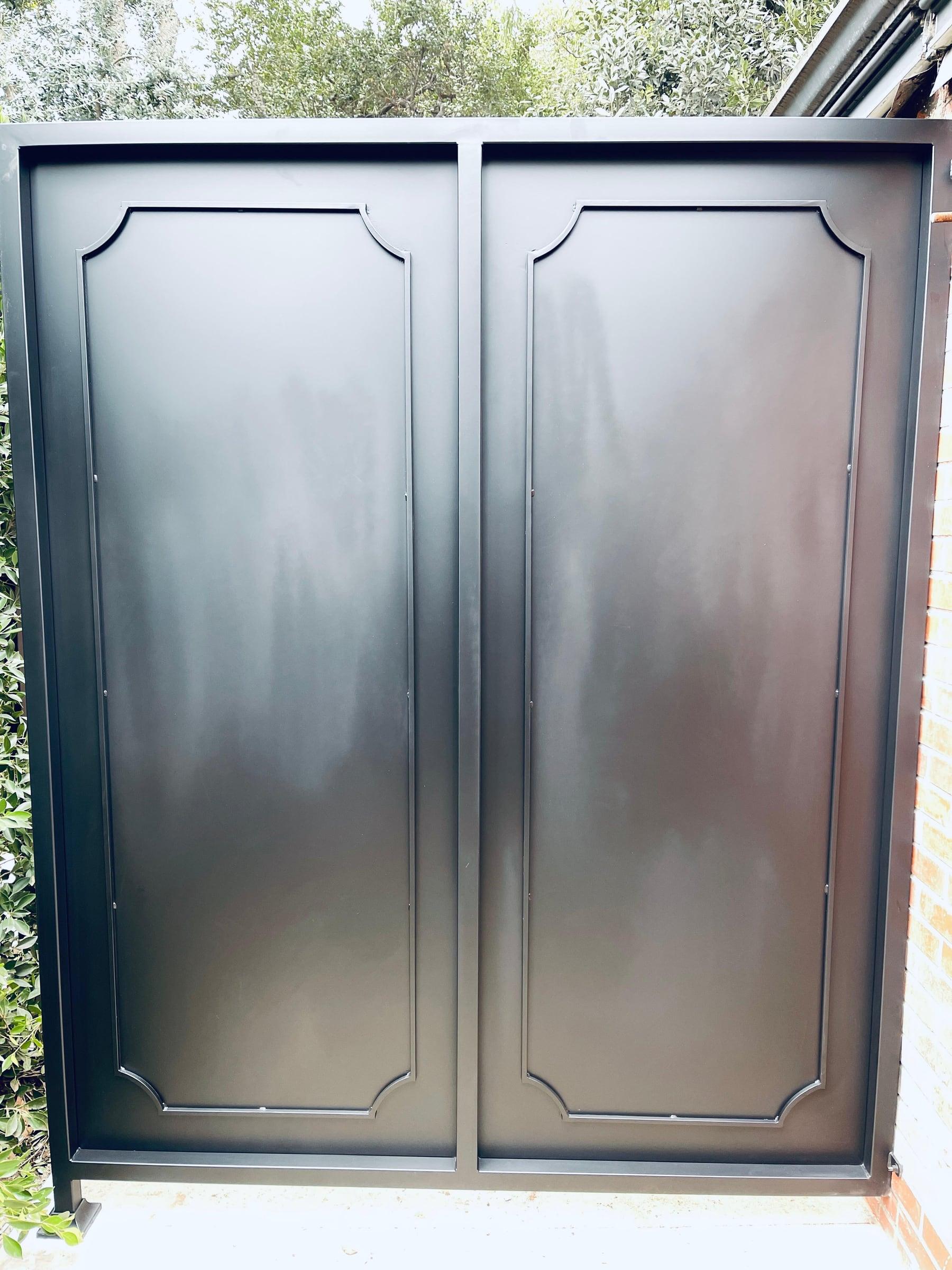 Double solid metal driveway gate with raised panel design
