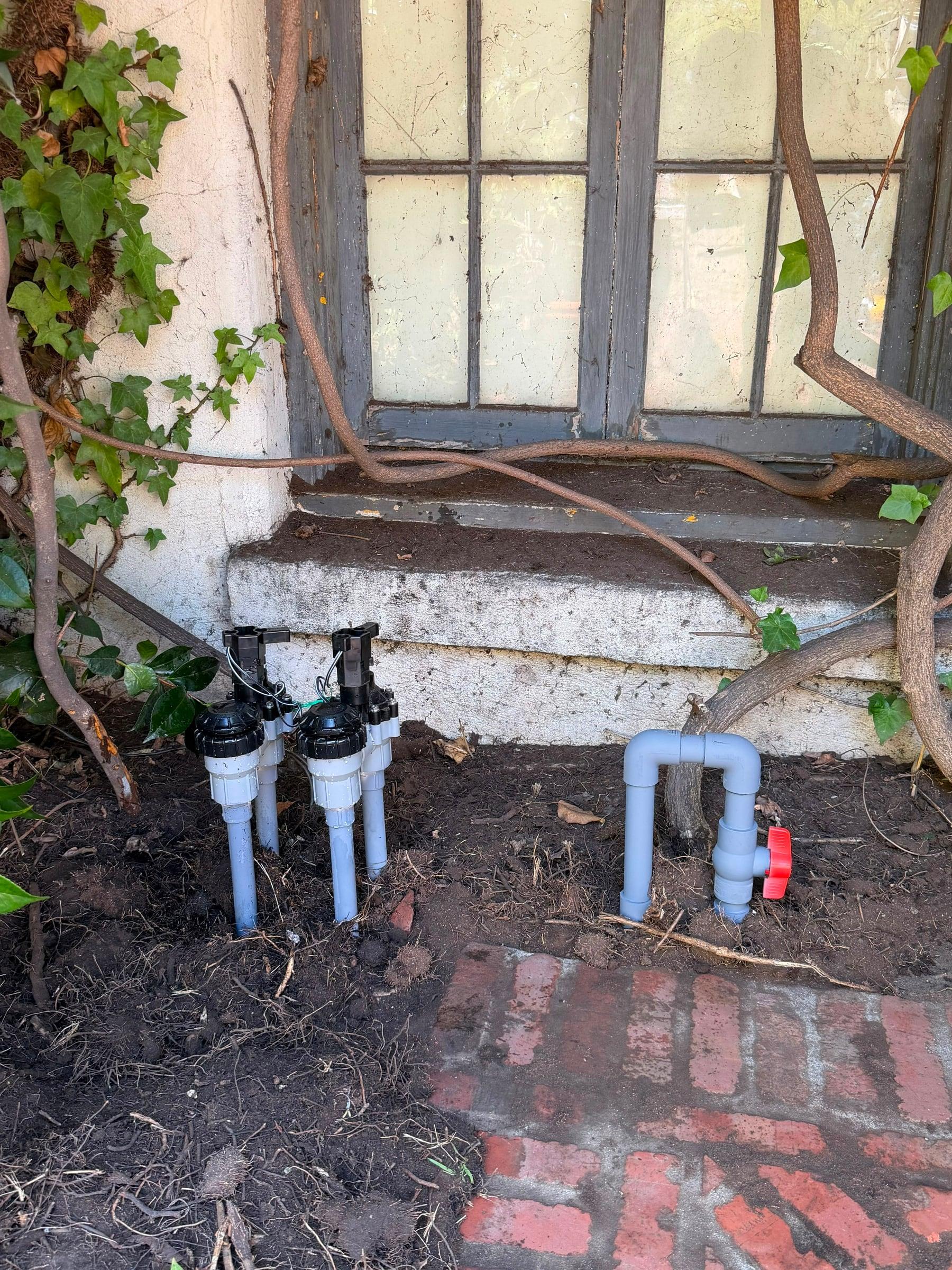 New anti-siphon valves wired near an existing shutoff in a side yard