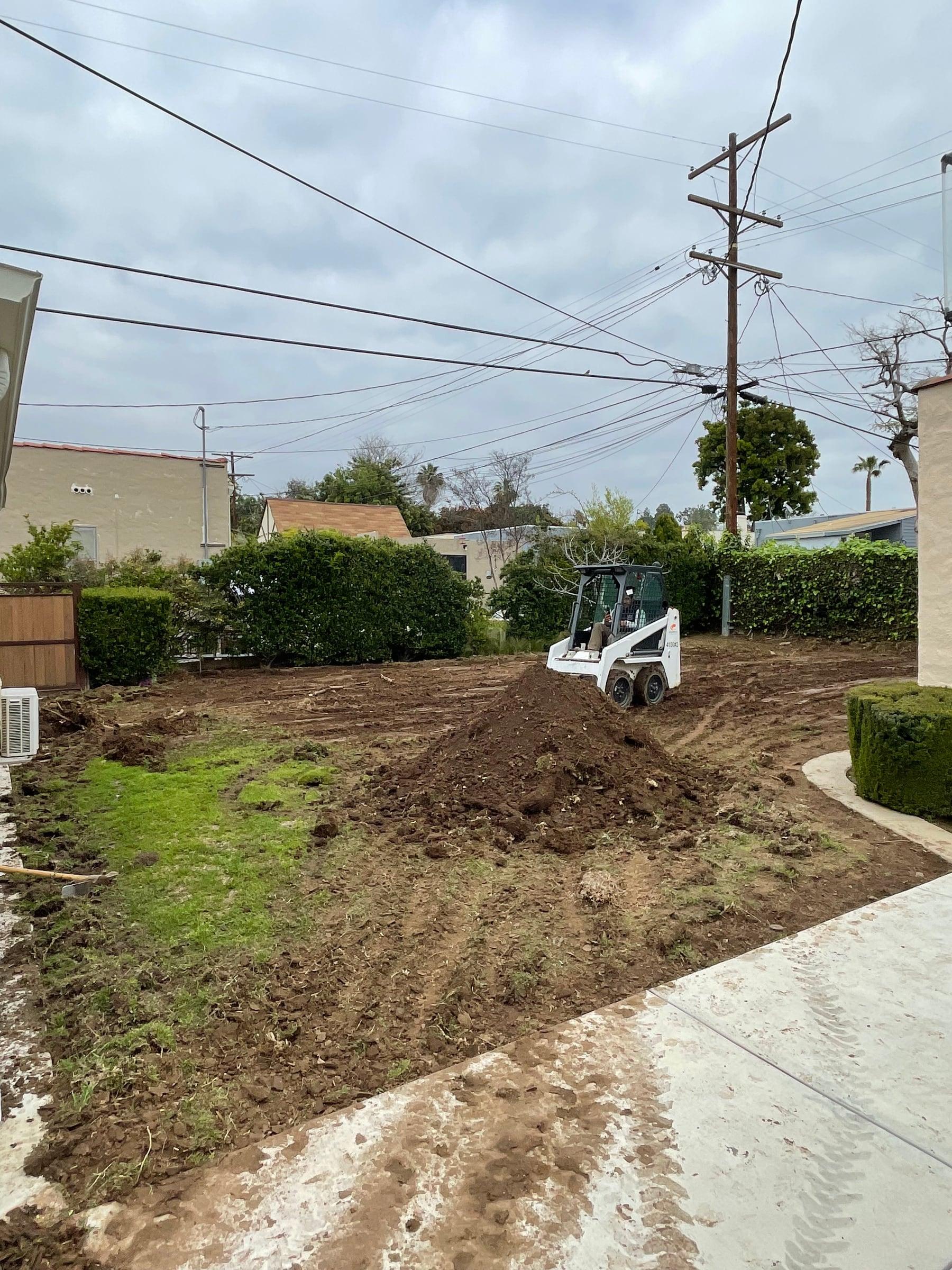 Skid steer grading a backyard for new landscaping