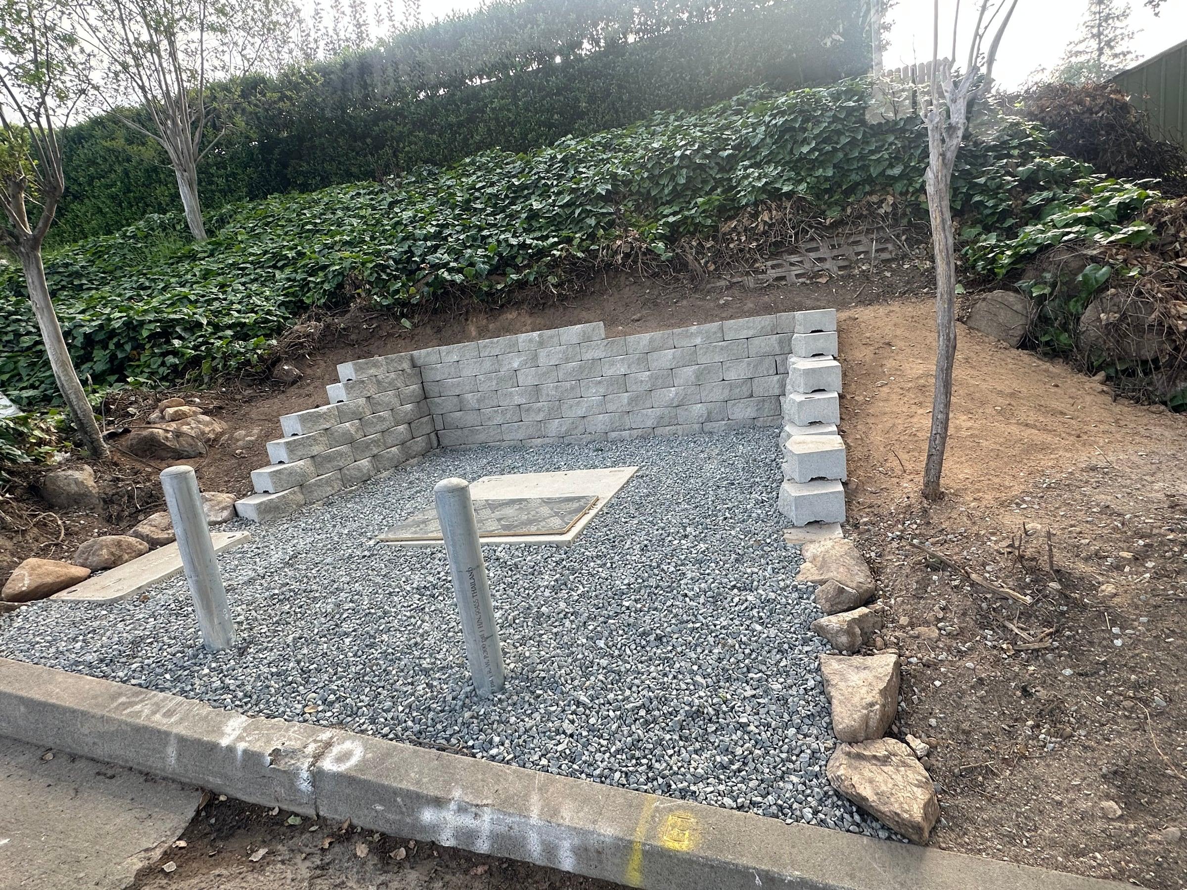 Concrete block retaining wall along a gravel parking area