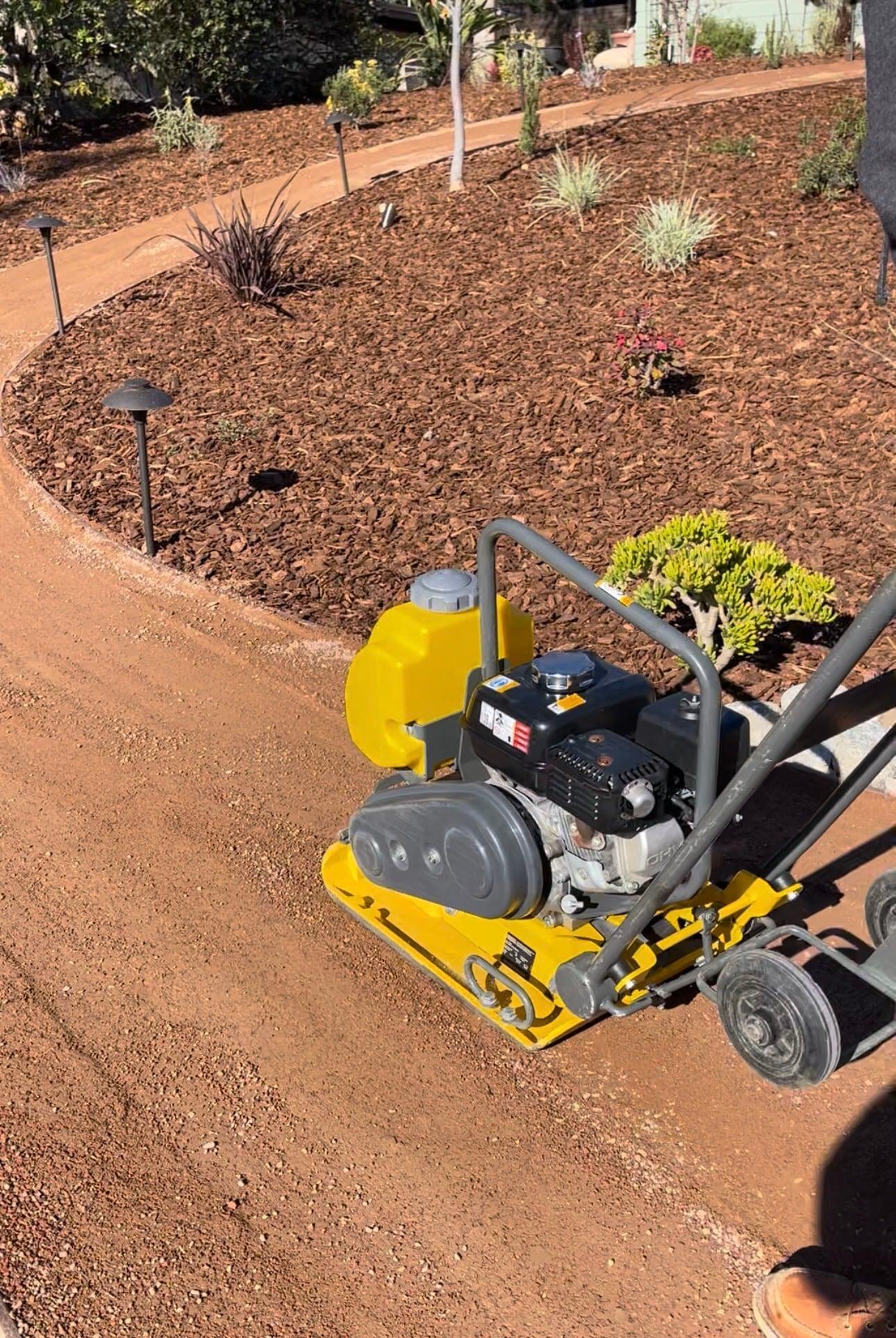 Compacting a decomposed granite pathway beside a planting bed