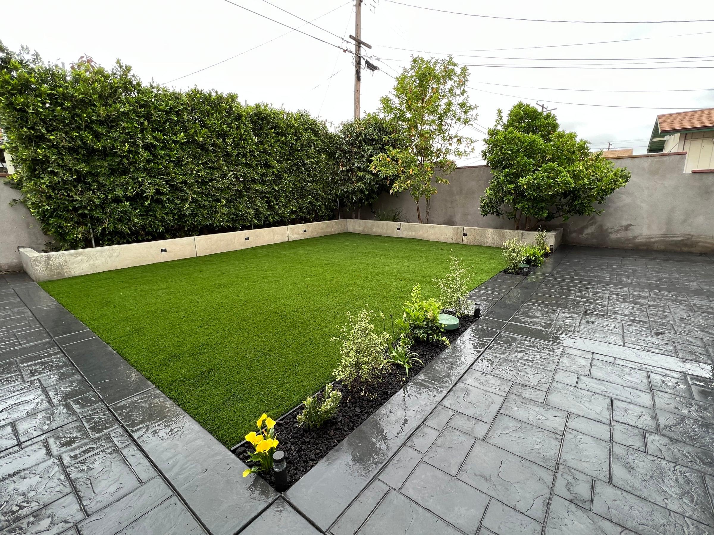 Backyard with artificial turf and a stamped concrete patio border