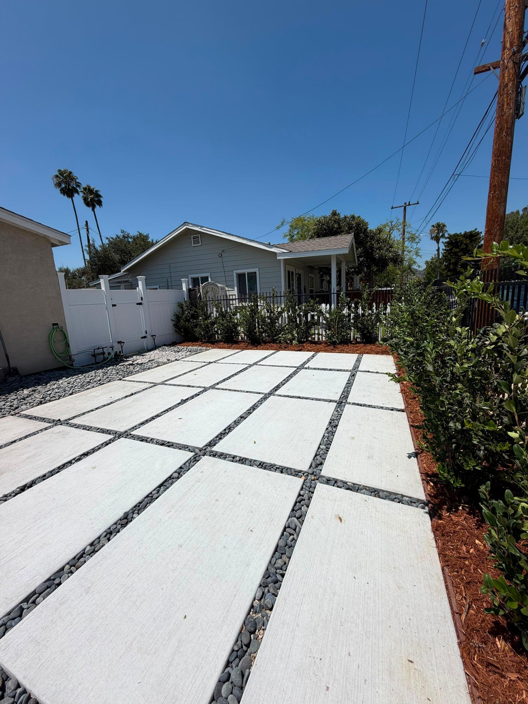 Backyard paver patio bordered by a boxwood hedge and fencing