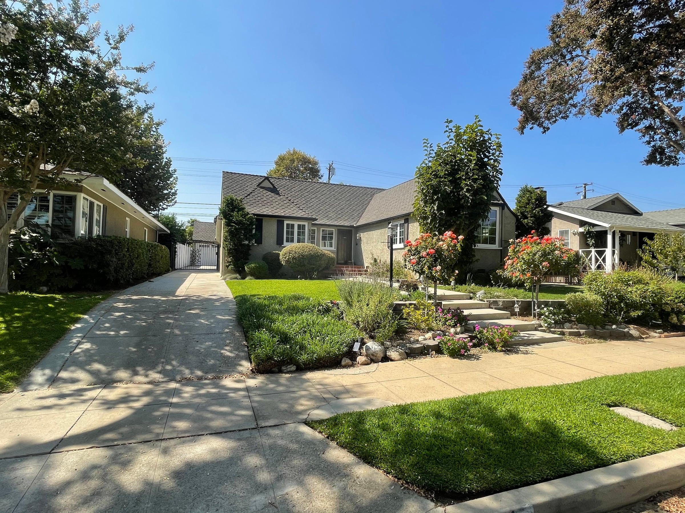 Manicured front lawn with rose trees and flowering beds