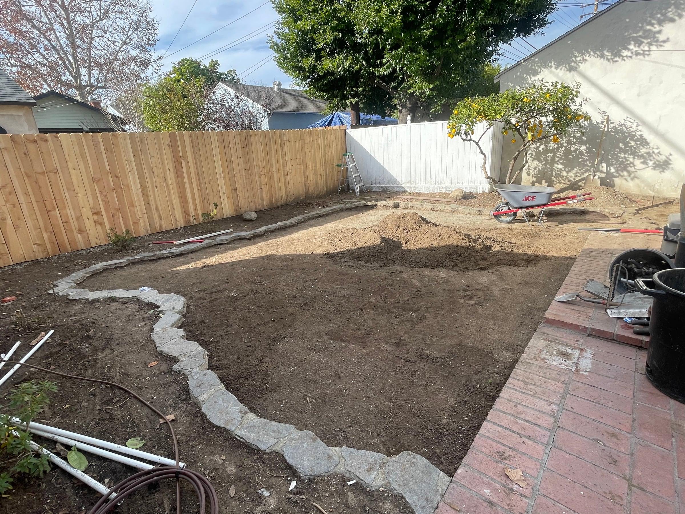 Backyard stone border being installed before grading and planting